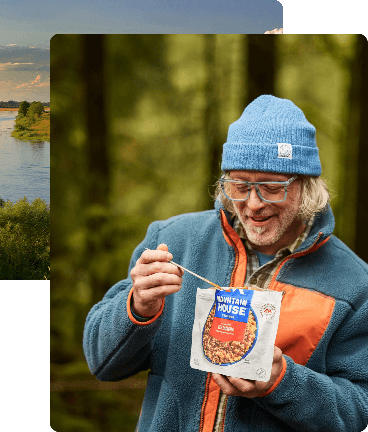 Person eating from a Mountain House pouch outdoors with a scenic river background