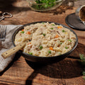 Bowl of creamy chicken and dumplings with vegetables on a wooden table