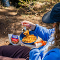 Girl scooping Chicken Fajita Bowl from a blue camping bowl at a campground.