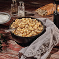 A bowl of Mountain House Beef Stroganoff on a wooden table with salt and pepper shakers.