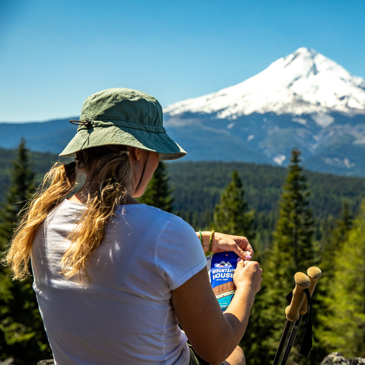 Girl opening pouch of Mountain House Mint Chocolate Chip Ice Cream Sandwich while hiking.