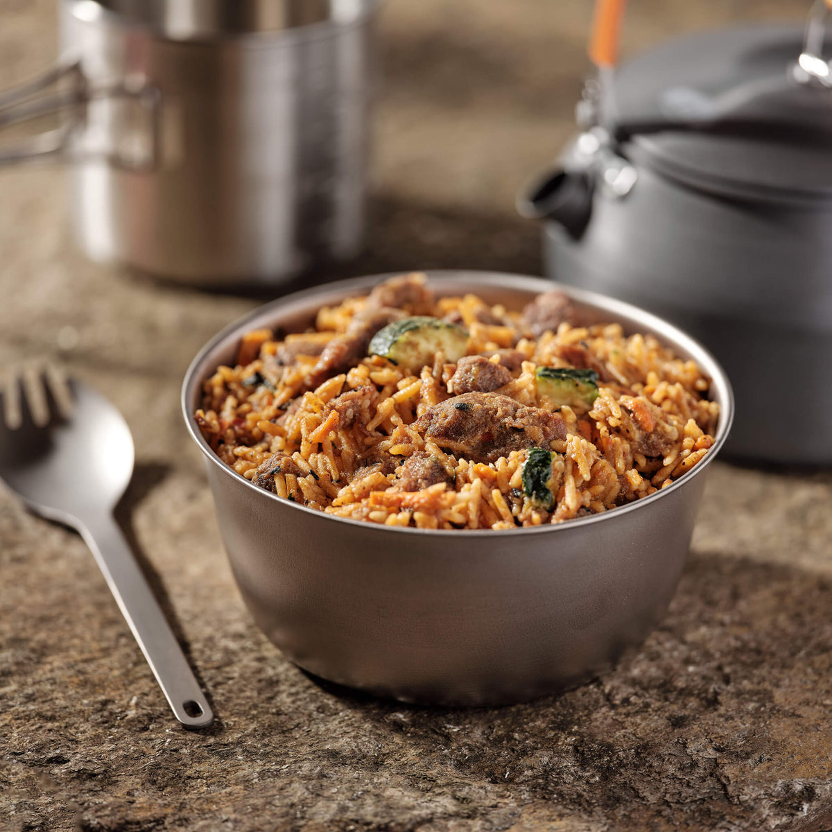 Bowl of Korean Beef with rice and vegetables on a countertop with a camp kettle and cup in the background.