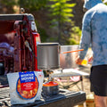 Camping stove and Mountain House Cheesy Pepperoni Pizza Bowl pouch on a tailgate.