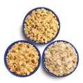 Three blue camping bowls, each filled with Mountain House Scrambled Eggs with Bacon, Breakfast Skillet, and Biscuits & Gravy.