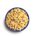 Blue camping bowl filled with scrambled eggs and bacon bits on a white background