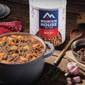 Mountain House Freeze-Dried Diced Beef on a wood countertop with a bowl of beef stew.
